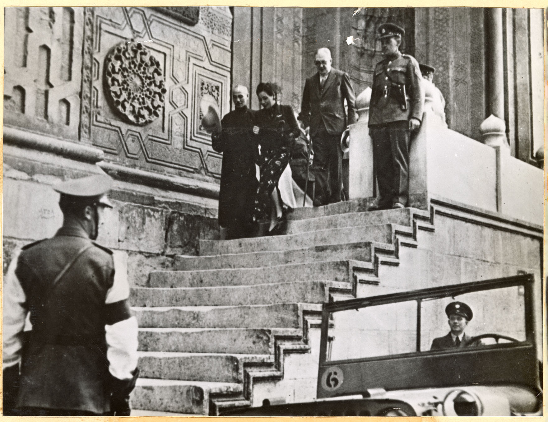 Chiang Kai Shek and his wife descend a staircase while other officers wait